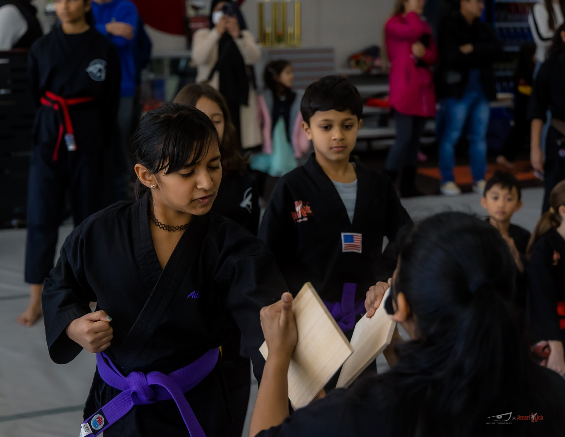 Students lined up taking turns breaking boards while families watch